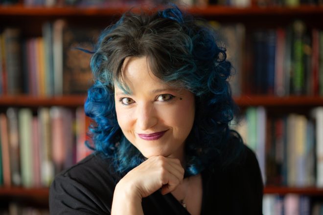 Alethea Kontis with her chin resting on her hand, looking at the camera